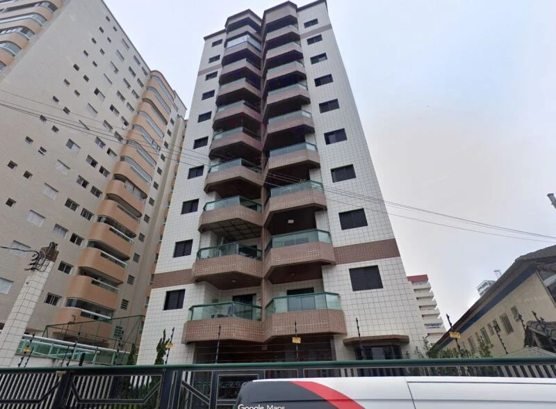 Apartamento branco com sacadas de vidro em prédio alto de fachada revestida em azulejos na avenida com prédios vizinhos