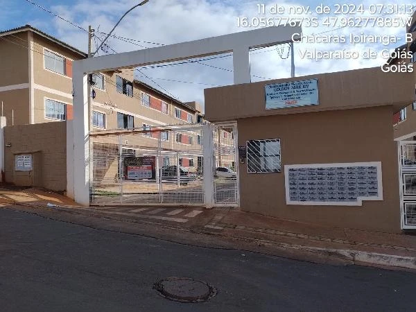 Apartamento bege em condomínio residencial fechado com portaria e vários blocos de três andares em rua asfaltada