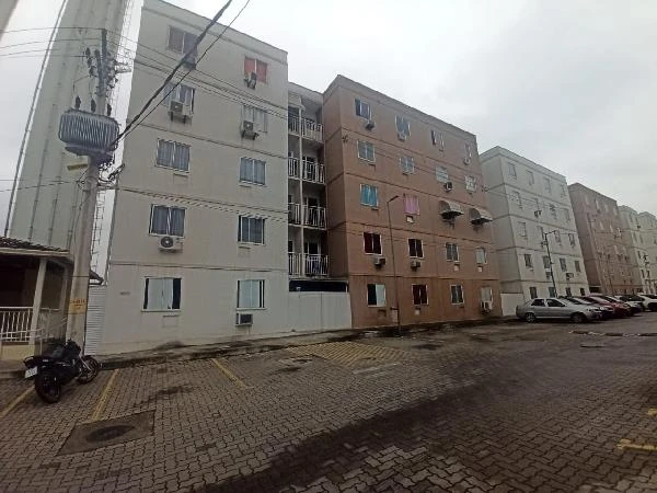 Apartamento com fachada em tons branco e bege, prédio de 4 andares em condomínio residencial com estacionamento externo