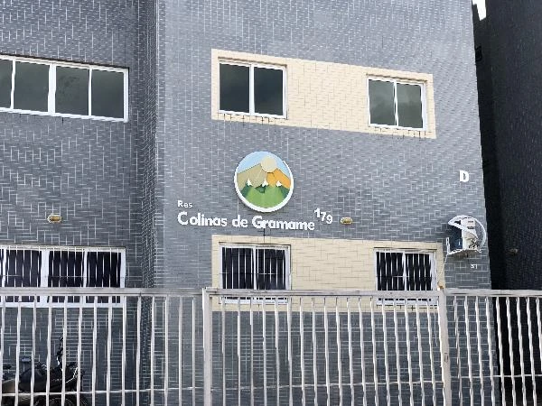 Apartamento cinza no condomínio residencial Colinas de Gramame com janelas brancas e portão frontal com grades