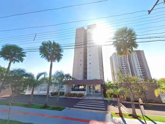 Apartamento beige de 77m² com uma vaga em condomínio com fachada alta e muro, entrada com paisagismo e palmeiras na frente