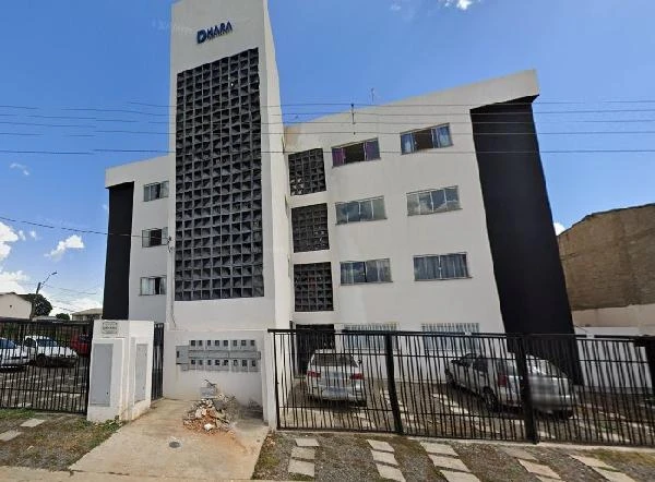 Apartamento branco de 49 metros quadrados com portão preto e garagem em prédio residencial de quatro andares