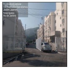 Apartamento branco em condomínio fechado com 4 andares, vaga de garagem com carro estacionado, rua interna e cercas de proteção