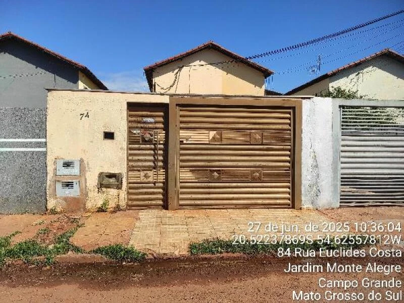 Apartamento com fachada simples em tom bege com portão metálico e muro baixo localizado em rua de terra