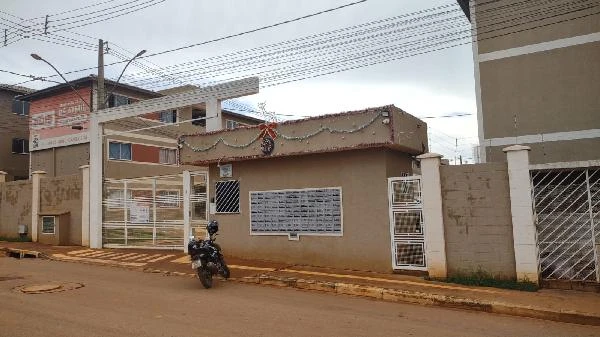 Entrada do condomínio residencial com portões e sinalização de leilão