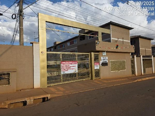 Apartamento com portão metálico dourado em condomínio residencial com fachada marrom e rua asfaltada