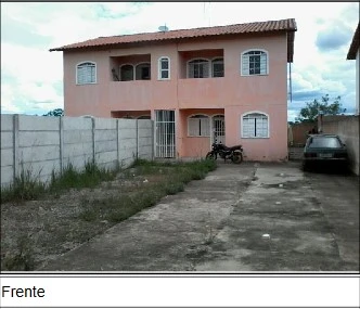 Apartamento rosa claro com varanda em condomínio residencial, frente com área de estacionamento e muro alto ao redor