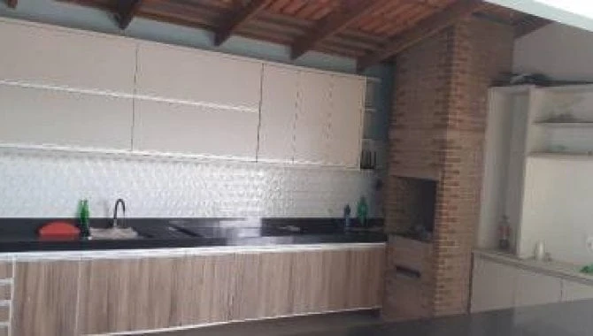 Apartamento padrão com área gourmet e churrasqueira em ambiente interno, paredes claras e balcões de madeira e branco