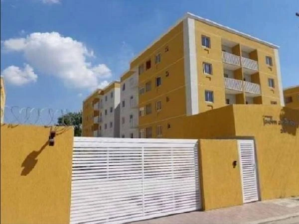 Apartamento amarelo em condomínio residencial com 4 andares e portão branco de entrada