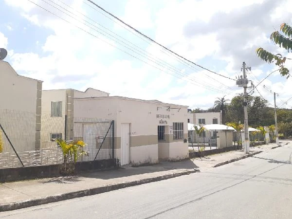 Apartamento branco com fachada simples em condomínio residencial em rua asfaltada com poucos carros