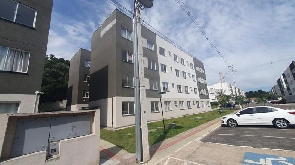 Apartamento com fachada cinza em condomínio residencial, áreas verdes e vagas de estacionamento externas