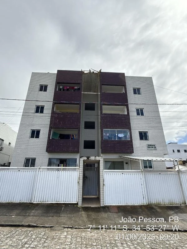 Apartamento em prédio de quatro andares com portão de entrada e fachada clara