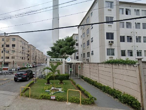 Apartamento branco em condomínio Residencial Bela Vida II com entrada principal e área verde frontal