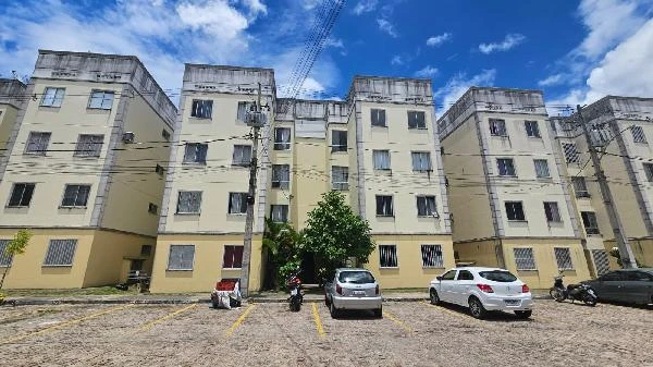 Apartamento amarelo claro com 2 quartos em condomínio residencial com área de estacionamento e carros estacionados