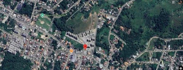 Apartamento localizado em área residencial com ruas e vegetação próximas visto de satélite