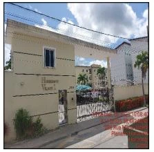 Apartamento em condomínio residencial com fachada clara e portão metálico, localizado em área urbana com árvores próximas