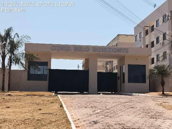 Apartamento em condomínio com portaria de entrada, muro e guarita, fachada clara e área seca ao redor