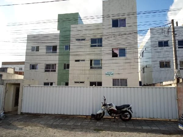 Apartamento claro com fachada em tons de verde e branco em condomínio Residencial Gabriela Visalli, com cerca metálica branca e moto estacionada em frente