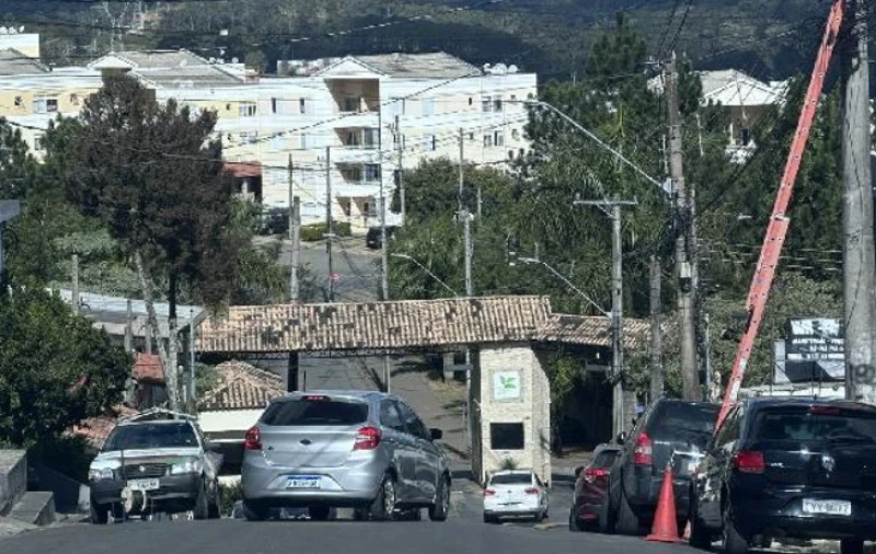 Apartamento cinza em condomínio com guarita e área urbanizada ao redor
