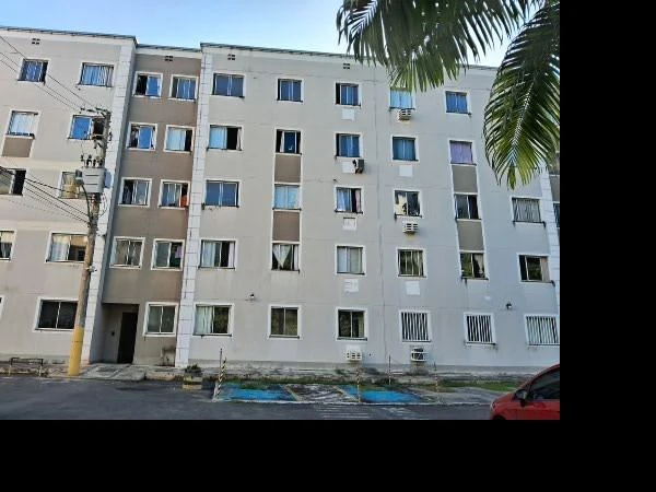 Apartamento branco de 4 andares com janelas e entrada visível em condomínio residencial visto da rua