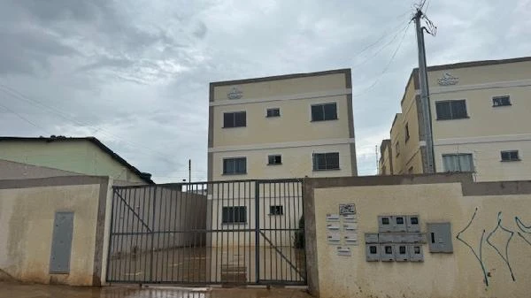 Apartamento bege em condomínio residencial com portão de metal e fachadas triplas em área urbana