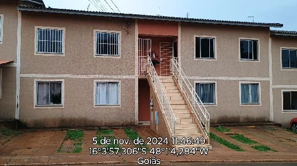 Apartamento bege em condomínio com dois andares e varanda central com escada externa fachada com pintura gasta