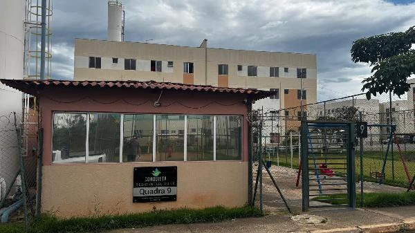 Apartamento com fachada clara e guarita na entrada em condomínio residencial sob céu nublado