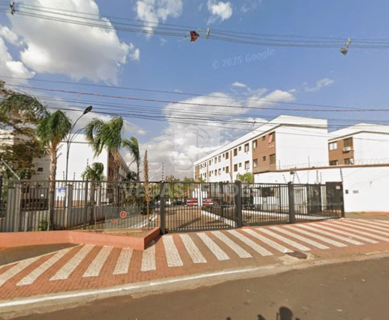 Apartamento branco em condomínio com portão de entrada gradeado e calçada larga no entorno