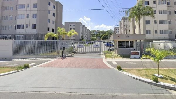 Apartamento com fachada de prédios residenciais brancos em condomínio fechado com entrada por portão automático e guarita