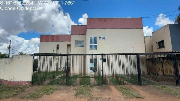 Apartamento bege com duas portas de vidro, portão de ferro preto e área gramada na frente em condomínio residencial