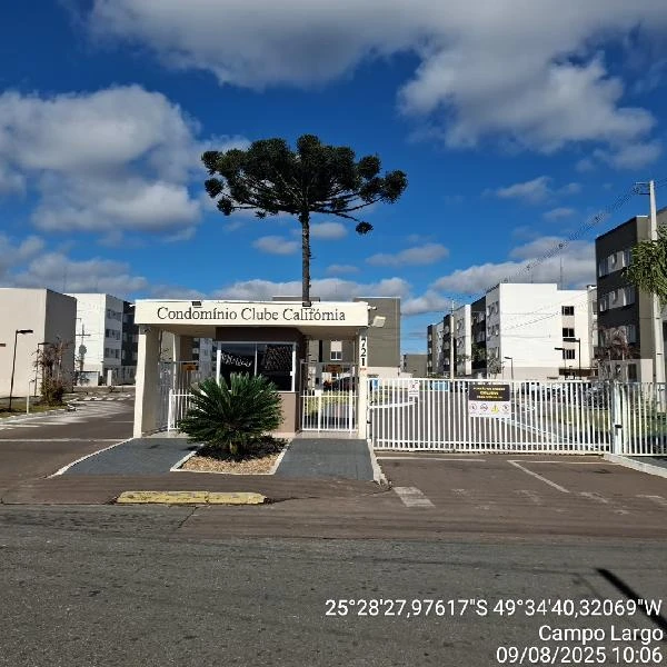 Apartamento no Condomínio Clube California com prédio branco e área de entrada com guarita e grade branca