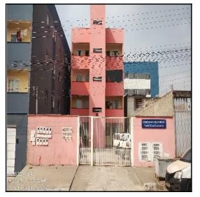 Apartamento rosa de 5 andares com fachada simples e grade branca na entrada em área urbana