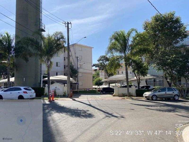 Apartamento branco em condomínio com áreas de estacionamento coberto e palmeiras no entorno