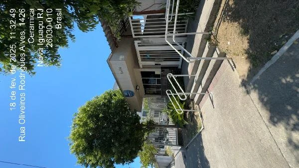 Apartamento branco em condomínio com grades de proteção e calçada pavimentada em área urbana