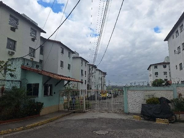 Apartamento branco em condomínio residencial com portão de entrada e guarita em área urbana