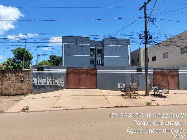 Apartamento cinza em condomínio residencial com portão de madeira e área externa pavimentada em Águas Lindas de Goiás