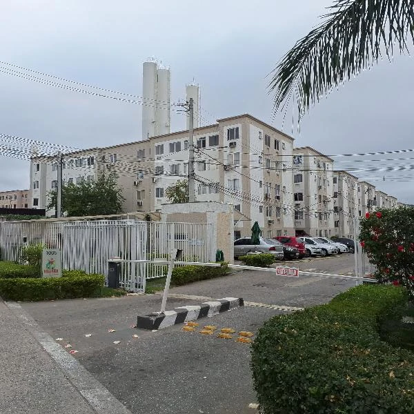 Apartamento em condomínio residencial com prédio bege de quatro andares e área de estacionamento com carros visíveis