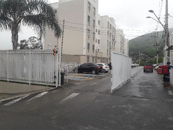 Apartamento branco em condomínio fechado com cerca metálica e área de estacionamento em Nova Iguaçu
