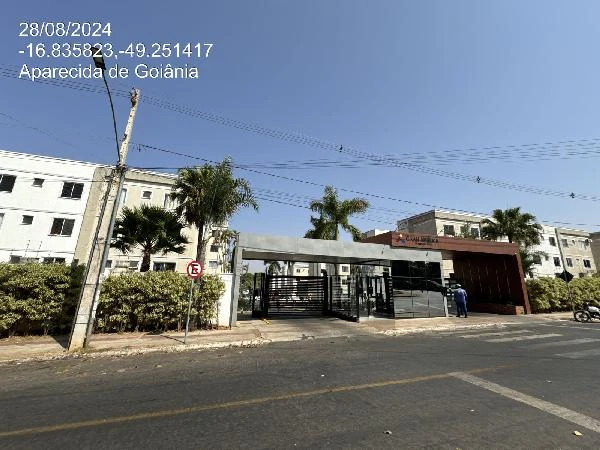 Apartamento branco com portaria automática em condomínio residencial com área ajardinada e rua asfaltada