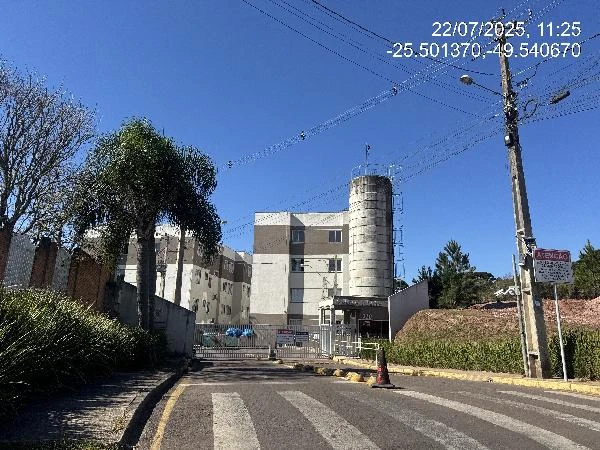 Apartamento branco em condomínio com torre cilíndrica e portaria, localizado em área urbana com vegetação local