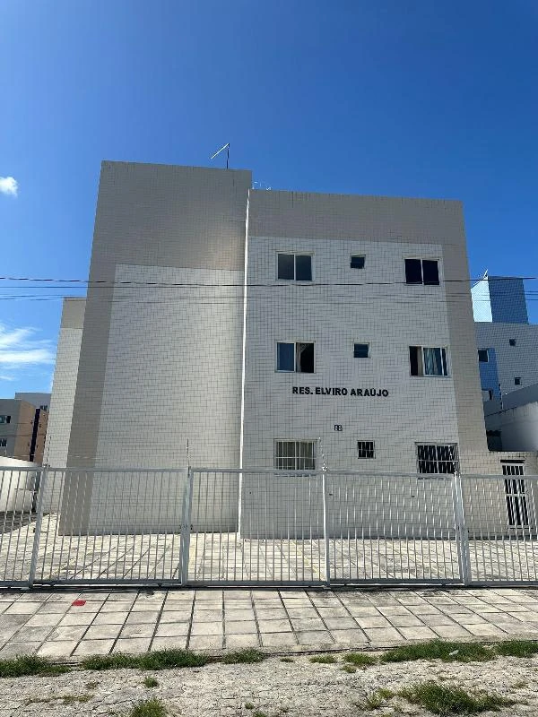 Apartamento branco em condomínio residencial com fachada revestida de azulejos brancos e portão de metal na frente