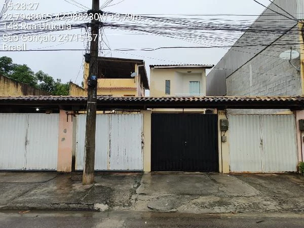 Apartamento com garagem e portões brancos e preto, fachada comum em área residencial urbana com muro ao redor