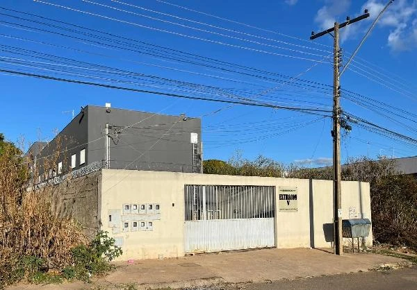 Apartamento cinza em condomínio residencial com cerca metálica branca e entrada com portão automático em área urbana