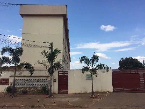 Apartamento branco de condomínio residencial com três pavimentos e portão vermelho em área urbana