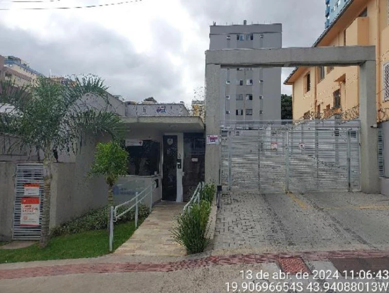 Apartamento cinza com portão metálico e guarita em condomínio urbano, fachada sem avarias visíveis