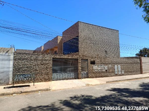 Apartamento com fachada de tijolos aparentes e portão metálico situado em rua residencial