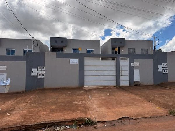 Apartamento cinza em condomínio residencial com portão branco e fachada moderna com área externa de terra