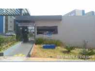 Apartamento bege com fachada simples e porteiro em condomínio, área externa com grama e floreira