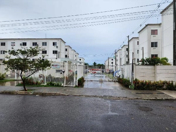 Apartamento branco de 41m² em condomínio residencial com grades na entrada em dia chuvoso