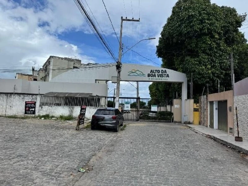 Entrada do condomínio residencial Alto Da Boa Vista com portão eletrônico e rua pavimentada com paralelepípedo e carro estacionado
